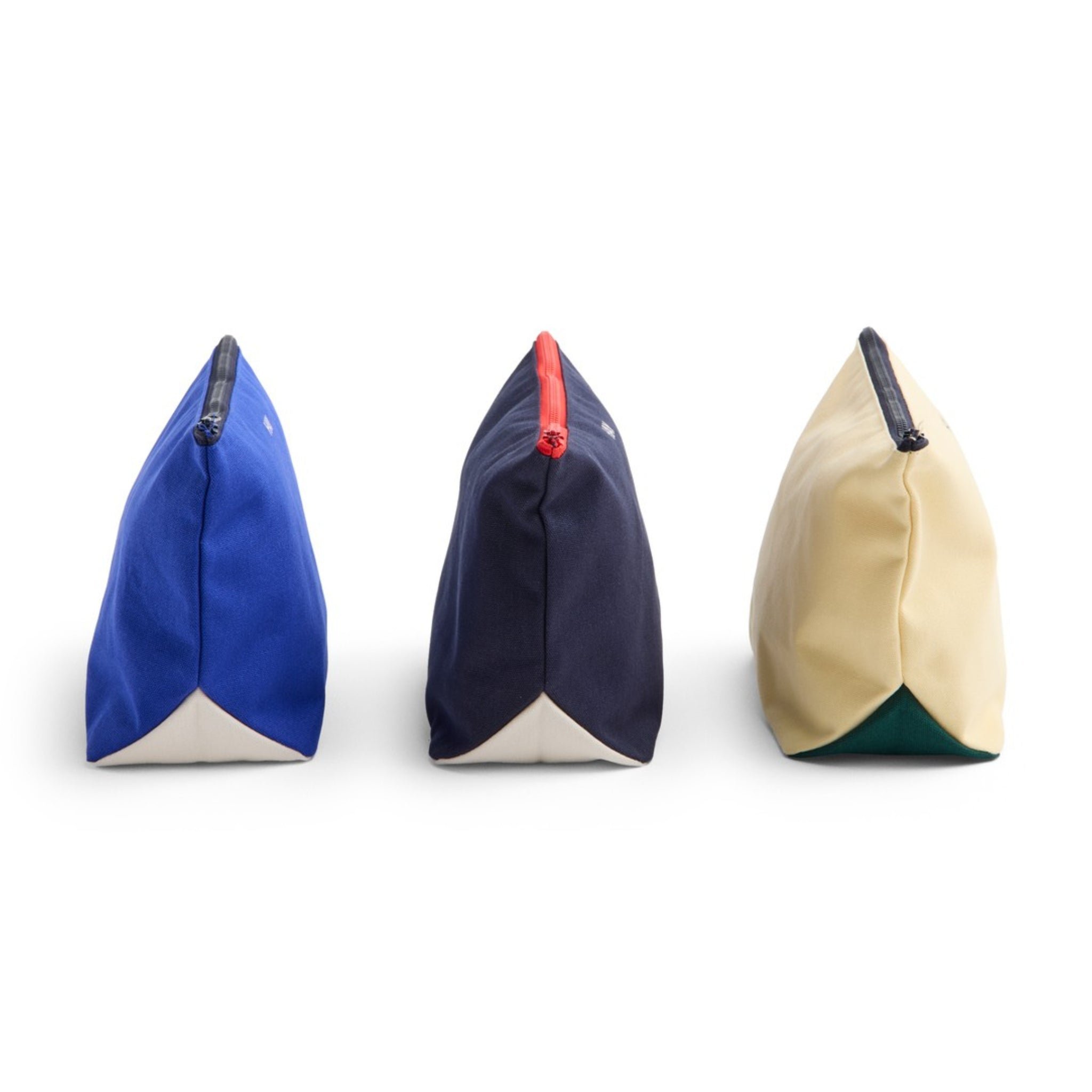 Drie driehoekige zakjes worden naast elkaar getoond, elk met een rits aan de bovenkant en een witte basis. Het Hay Multi Opbergzakje Geel M van Hay is er één van, met Scandi design in geel naast blauwe en donkere navy opties.