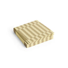 Een stapeltje Hay Pattern Papieren Servetten Crème Zand Stripe 33/33 van Hay, met een crème zand streepmotief, netjes gerangschikt op een witte achtergrond.