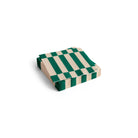 Een stapel Hay Pattern Papieren Servetten Off-white Groen 25/25 van Hay, met groene strepen op een gebroken witte ondergrond, is netjes gerangschikt op een witte achtergrond. FSC gecertificeerd voor verantwoord materiaalgebruik.