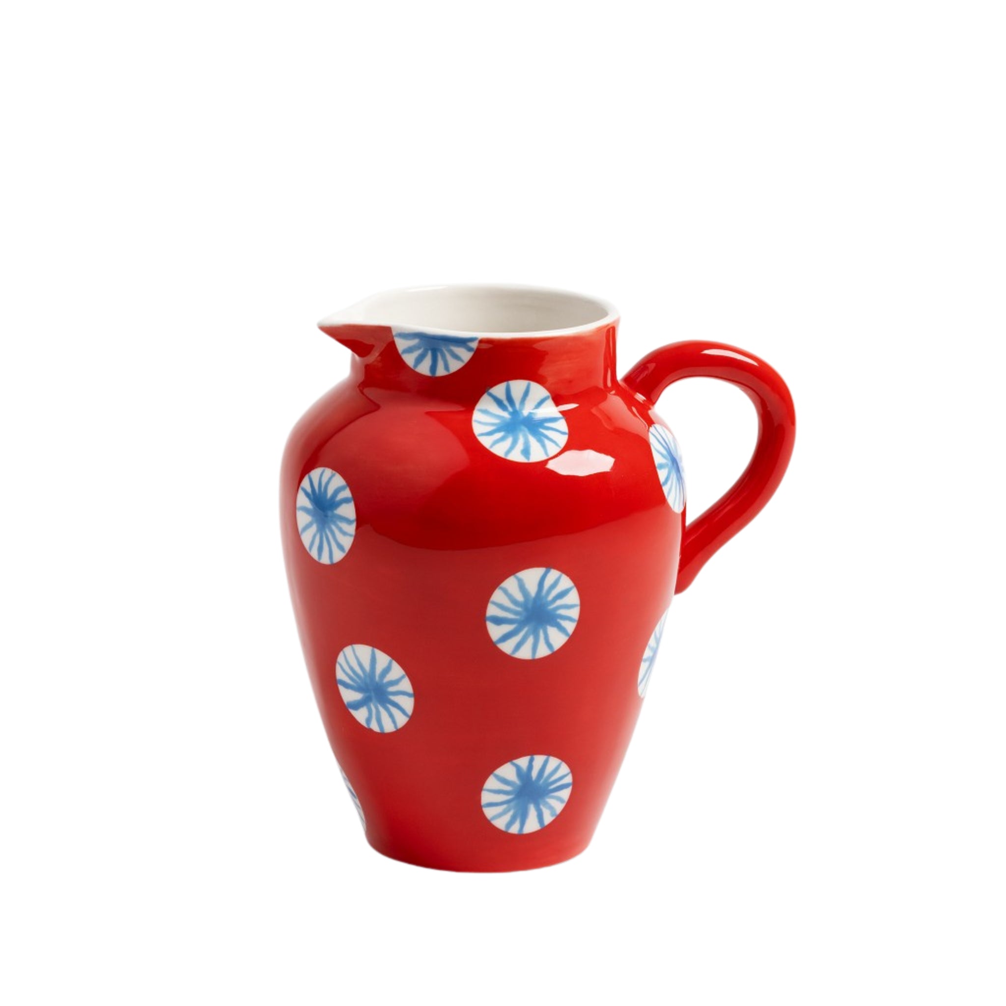 De &Klevering Festivo Kan Rood 1,5L heeft een gebogen handvat en is versierd met blauwe en witte cirkelvormige patronen op rood; de binnenkant van dit decoratieve object van &Klevering is wit.