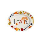 De &Klevering Haines Schotel 28/22 van &Klevering is een charmante ovale porseleinen schaal met kleurrijke herfstmotieven, zoals sinaasappelbomen, een ladder, sokken aan een waslijn, appels, bessen en vallende bladeren - in geschenkverpakking.