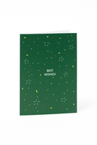 De Matriks Kerst- en Nieuwjaarskaart Best Wishes! heeft een groen ontwerp van Julie Lindekens, met rode, gele en witte confetti-achtige vormen en vetgedrukte witte "BEST WISHES!" tekst in het midden. Merk: Matriks.