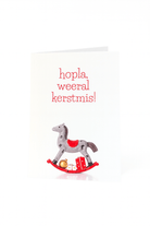 De Matriks Kerstkaart Hopla Weeral Kerstmis! van Matriks toont "hopla, weeral kerstmis!" boven een illustratie van een grijs-rood hobbelpaard met cadeautjes en een unieke kerstbal.