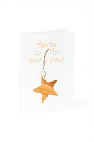 Stuur feestelijke wensen met de Matriks Nieuwjaarskaart Cheers to the New Year! kaart, met een uniek kerstbal houten ster ornament en "cheers to the new year!" in geel op een witte achtergrond.