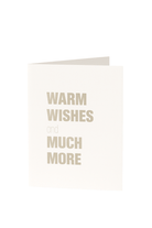 Een witte Matriks Kerst- en Nieuwjaarskaart uit de Matriks collectie staat rechtop met "Warme wensen en nog veel meer!" in dikke beige letters op de voorkant.