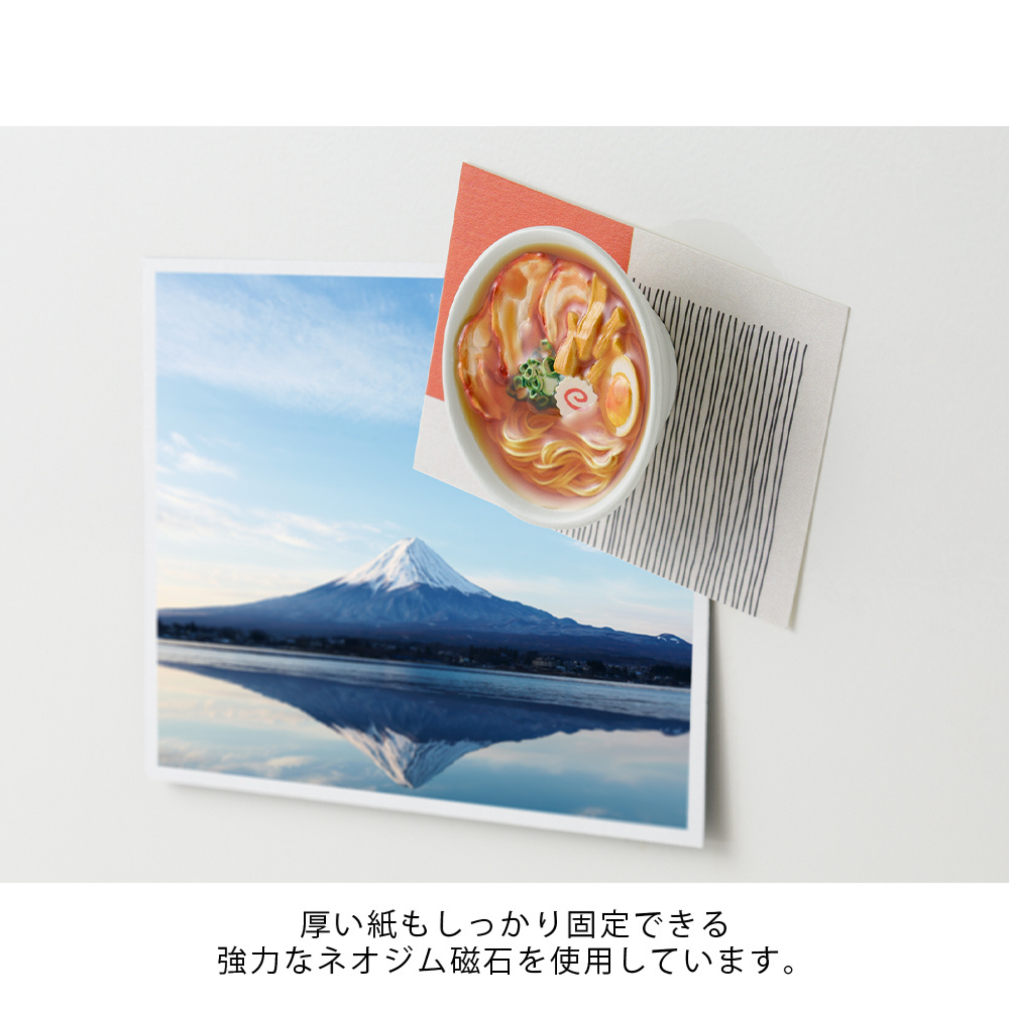 Een foto van Mount Fuji en een ansichtkaart zijn vastgezet op een wit oppervlak door de Midori Miniatuur Magneet Ramen, met een ramen bowl design. Onder de afbeelding staat Japanse tekst.