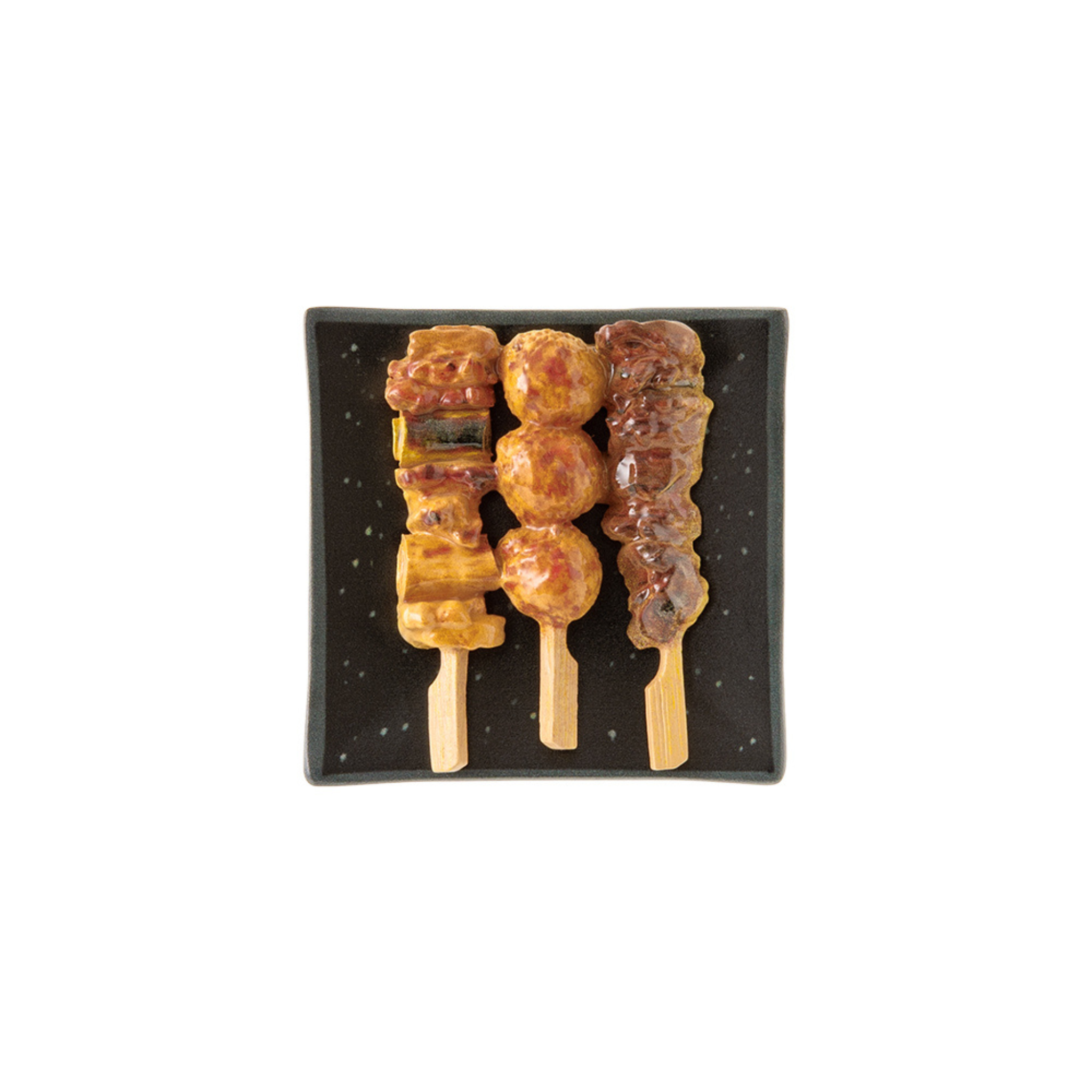 Drie spiesjes van gegrild vlees en groenten, geïnspireerd op de Midori Miniatuur Magneet Yakitori, zijn kunstig gerangschikt op een vierkant zwart bord - de perfecte Japanse koelkast magneet van Midori voor je verzameling.