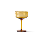 De Paveau Swirl Champagne Coupe Dune Geel 26 cl van Paveau is een amberkleurig borosilicaatglas met een brede kom, slanke steel en ronde voet, weergegeven op een effen witte achtergrond.