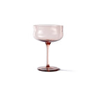 De Paveau Swirl Champagne Coupe Silt Bordeaux 26 cl van Paveau heeft een doorschijnende roze kom en slanke steel, gemaakt van borosilicaatglas - ideaal voor feestelijke gelegenheden. Afgebeeld tegen een effen witte achtergrond.