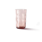 De Paveau Swirl Longdrink Glas Silt Bordeaux 46 cl van Paveau, met een doorschijnende roze tint en een golvend gestructureerd oppervlak, staat rechtop op een witte achtergrond met een zachte schaduw naar rechts.