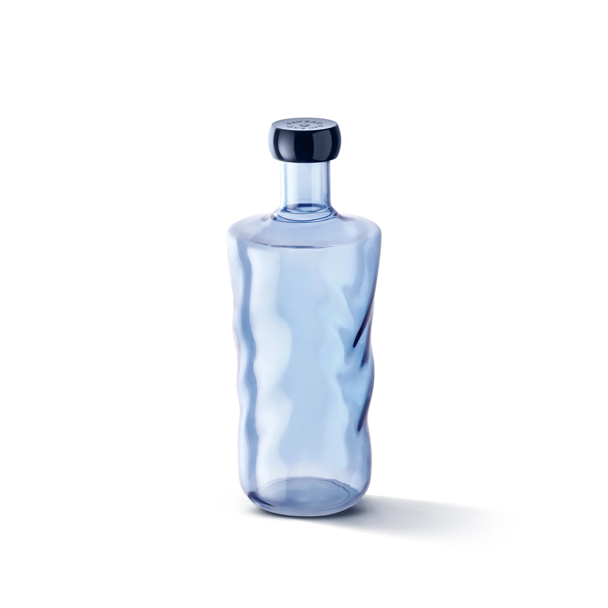 De Paveau Swirl Waterfles Midnight Blauw 1,25 l van Paveau is een doorschijnend blauwe borosilicaat glazen fles met golvende zijkanten en een bijpassende ronde stop, weergegeven op een witte achtergrond.