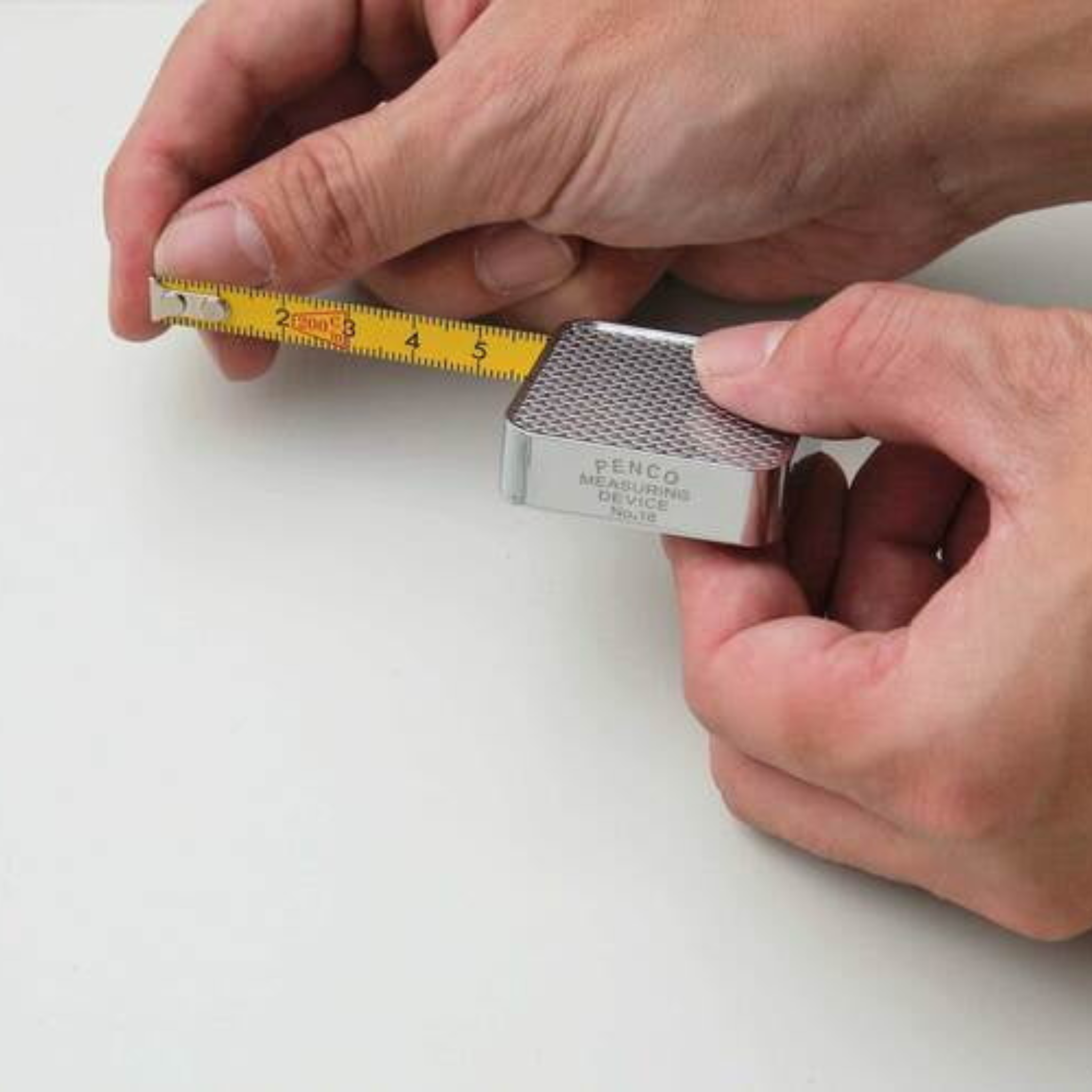 Een persoon houdt de Penco Compacte Rolmaat Zwart vast en trekt het gele meetlint uit-een handig, compact hulpmiddel van Penco met zwarte details, ideaal voor nauwkeurige metingen onderweg.