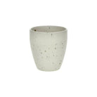 De Pomax Bosque Beker Wit H10 van Pomax is een kleine, ronde, lichtgrijze beker van keramiek met een matte afwerking en subtiel gespikkeld patroon, afgebeeld tegen een effen witte achtergrond.