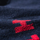 Close-up van de getextureerde Puebco Badmat Gerecycleerd Garen Blauw 75/45, met de donkere stof van gerecycled garen en een levendige rode letter E, met de nadruk op het weefsel en het contrast tussen het rode detail en de diepblauwe achtergrond.