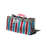 Een Puebco Gerecycleerde Tas Strepen Rood Blauw Breed van Puebco heeft opvallende blauwe, rode en roze strepen, een roze plastic handvat en een label met 503189, gefotografeerd op een witte achtergrond.