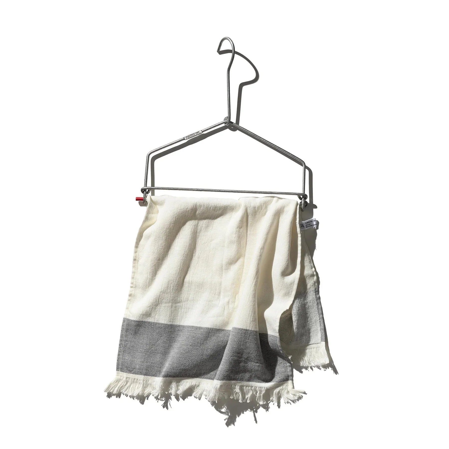 Een lichtgewicht witte handdoek met franjes en een grijze streep hangt aan de Keukenrolhouder Hanger van Puebco, met een minimalistisch ontwerp tegen een effen witte achtergrond.