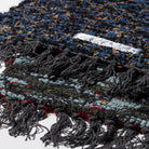 Een close-up van de Puebco Mat Gerecycleerd Textiel 63/41 van Puebco, met de veelkleurige geweven draden-blauw, zwart, rood, geel-omzoomde randen en een klein wit label met gedeeltelijk zichtbare tekst.