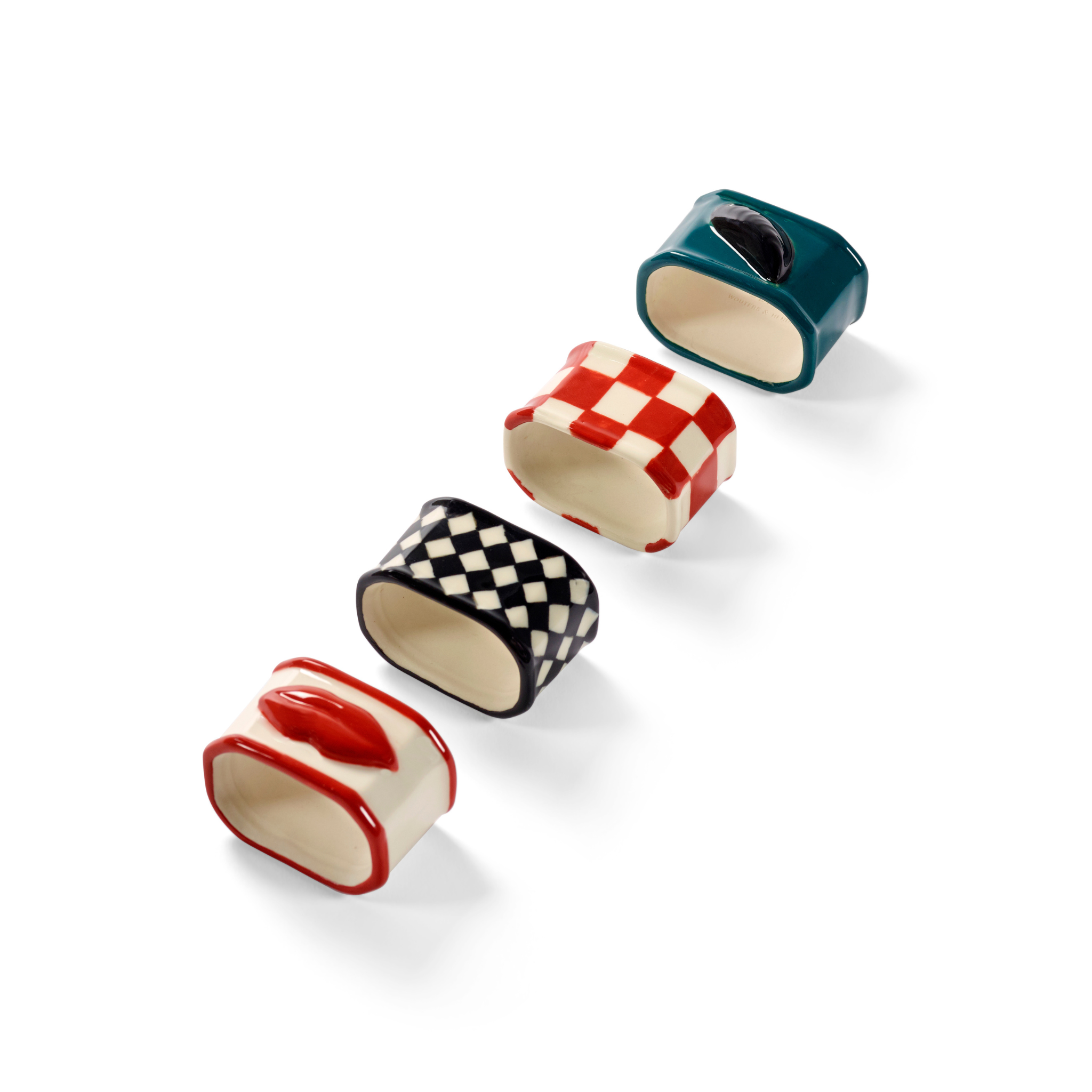 Vier Serax Wouters & Hendrix Servetring servetringen (set van 4) in dambord en effen rode, zwarte en groenblauwe motieven zijn diagonaal gerangschikt op een witte achtergrond - ideaal voor een stijlvolle tafelschikking.