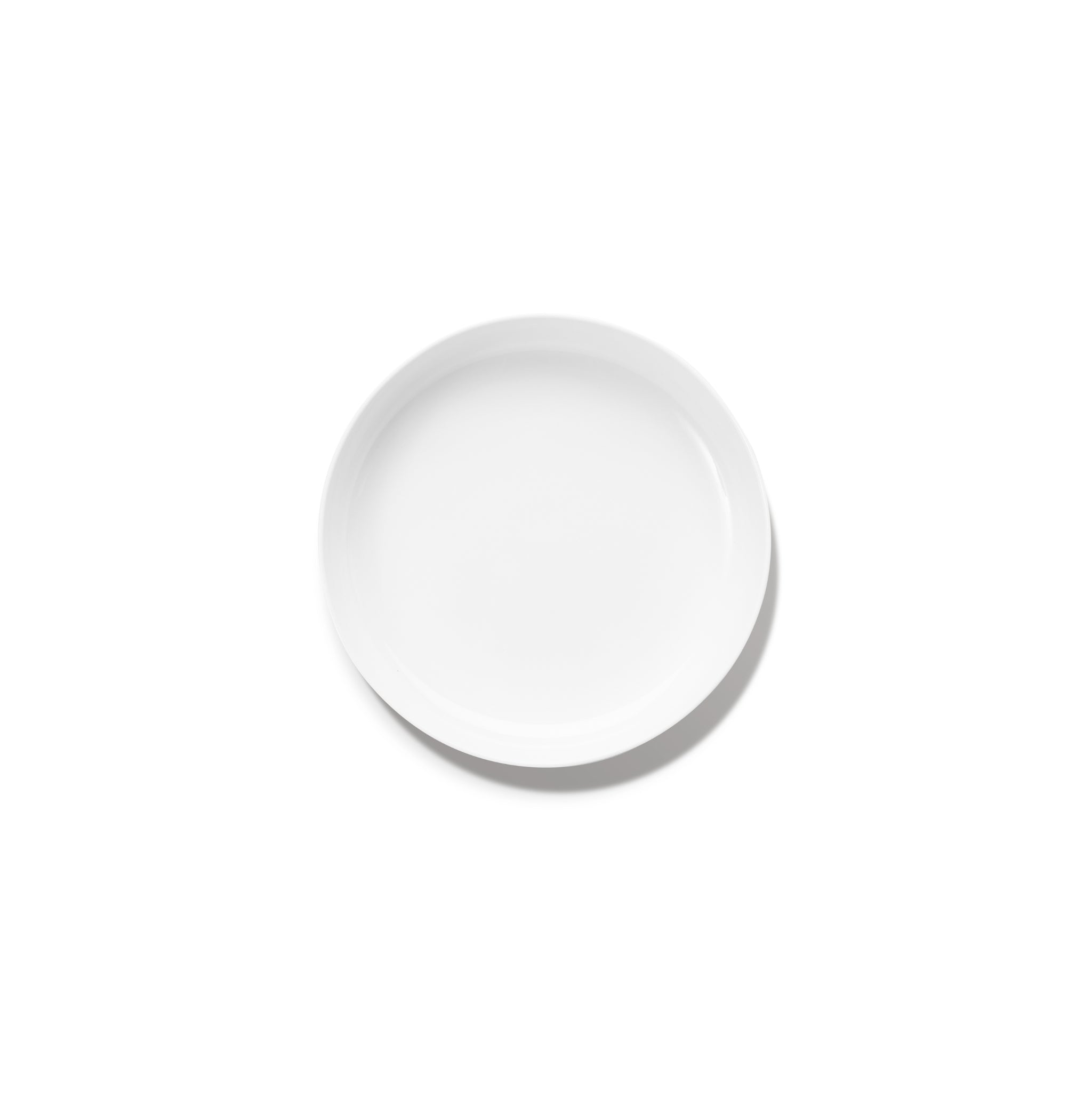 Een Serax Base Diep Bord D24, een rond wit keramisch bord van Serax, is gecentreerd op een witte achtergrond met een vage schaduw linksonder.