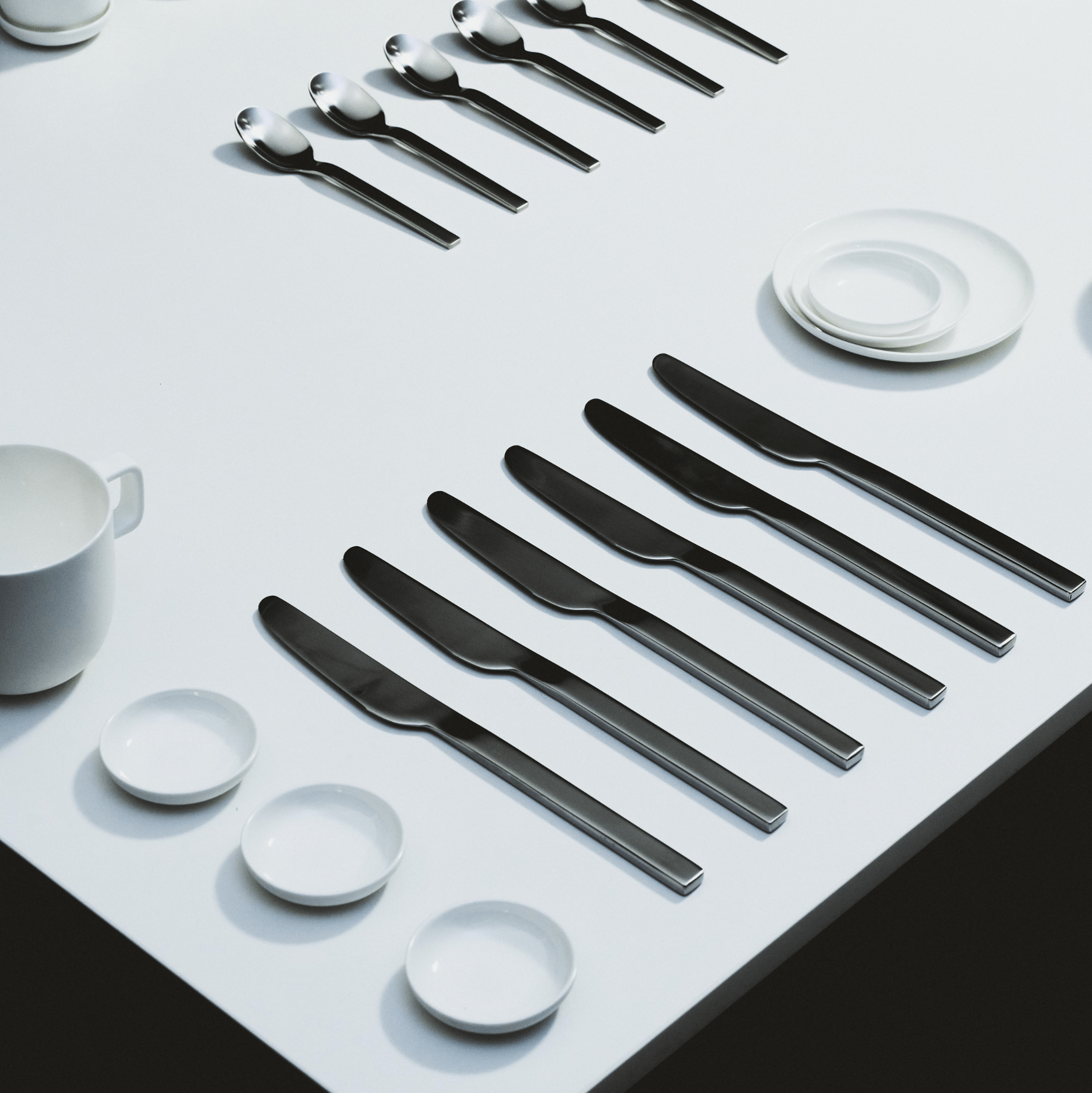 Verschillende Serax Base Theekop met Oor 35 cl staan netjes in parallelle rijen op een witte tafel, waardoor een minimalistische en georganiseerde compositie ontstaat.