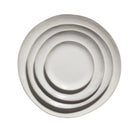 Drie Serax La Mère Laag Bord Wit D14,5 borden van Serax zijn gestapeld in concentrische cirkels en van bovenaf bekeken op een witte achtergrond.