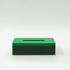 De Wavy Tissuebox Highland/Pearl Groen van Wavy Design Studio is een rechthoekige, groene, geribbelde tissuebox met een horizontale gleuf aan de bovenkant, gemaakt van gerecycled hout voor een duurzaam ontwerp, afgebeeld tegen een effen witte achtergrond.