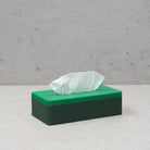De Wavy Tissuebox Highland/Pearl Groen van Wavy Design Studio is een groene rechthoekige tissuebox gemaakt van gerecycleerd hout, voorzien van een enkele witte tissue en ideaal voor liefhebbers van duurzaam design.