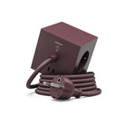 De Avolt x Bauhaus Archiv Square 1 USB-C Stekkerdoos in Mulberry Rood (1,8 m) heeft meerdere stopcontacten en een USB-C poort, met de stekker en het snoer netjes opgerold rond de basis.