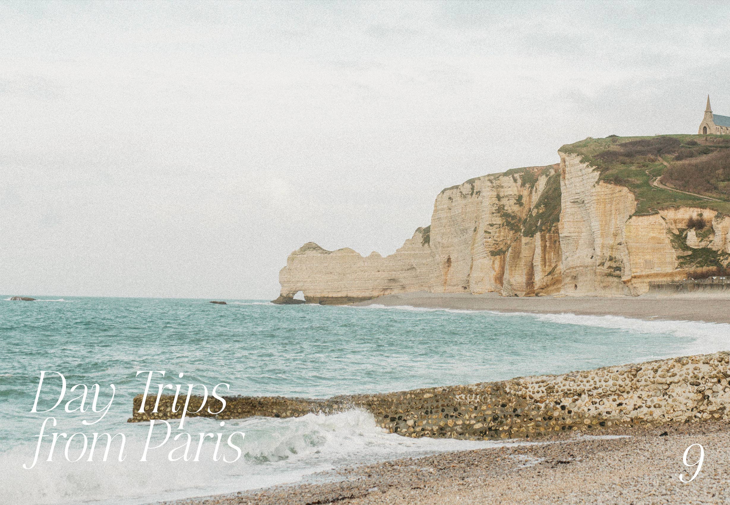 Rotsachtige kliffen ontmoeten turquoise zee onder een bewolkte hemel, met een kapel erboven en golven op een kiezelstrand. Ontdek de beste tips van Cozy Publishing Parijs Dromerige tips voor de stad van de liefde Reisgids-"Dagtochten vanuit Parijs 9" in het wit in de benedenhoeken.