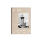 De Cozy Publishing Parijs Dromerige tips voor de stad van de liefde Reisgids bevat insider tips op een beige omslag met textuur en een zwart-wit foto van een Parijs monument en de Eiffeltoren op de achtergrond.