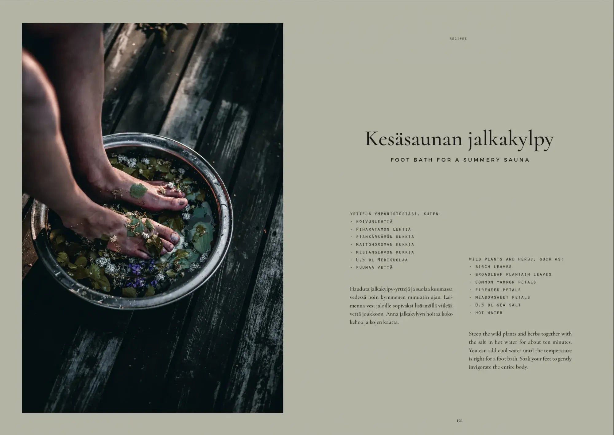 Een persoon laat zijn voeten weken in een metalen bak met water, bloemblaadjes en bladeren op donker hout terwijl de Finse en Engelse tekst het Cozy Publishing Sauna Boek voetenbad ritueel beschrijft voor een verfrissende zomerse sauna ervaring.