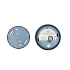 Twee ronde apparaatvoeten naast elkaar: de ene is een Jacob Jensen Optical Rookmelder Blauw D10 met etiket, schakelaars en groene indicator; de andere toont alleen de effen koperen onderkant met sleuven. Merk: Jacob Jensen.