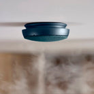 Een slanke Jacob Jensen Optische Rookmelder Blauw D10 is aan het plafond gemonteerd, met daaronder rookdetectie. Dit toont de stijlvolle blauwe rookmelder van Jacob Jensen in actie.