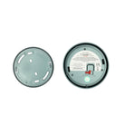 Twee ronde objecten op een witte achtergrond: links zie je een effen deksel met gleufjes, rechts de achterkant van de Hoptimist Jacob Jensen Optical Rookmelder Groen D10, met Scandinavische designelementen zoals een schakelaar, label en batterijvakje.