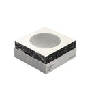 De Jacob Jensen Optical Rookmelder Zilver D10 heeft een Scandinavisch ontwerp, met een vierkante vorm, een slanke witte en grijze verpakking en een ronde sensor van zilvergaas bovenop, tegen een effen witte achtergrond.