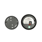 Er zijn twee ronde zwarte plastic objecten te zien: links een gewoon deksel met sleuven en rechts de achterkant van een Jacob Jensen Optical Rookmelder Zwart D10 met een label, rode schakelaar en aan/uit-markering.