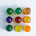 Negen levendige, doorschijnende bollen, elk geplaatst op een vierkante pastelkleurige voet en gerangschikt in een raster van 3 bij 3, weerspiegelen de speelse esthetiek van de Matias Moellenbach OBA Zeep Bar Aloe Vera. Elke bol heeft een unieke tint – waaronder groen, geel, oranje, rood en paars – die aansluit bij de levendige kleuren van de vaste zeep van Matias Moellenbach en zachte schaduwen werpt op een witte achtergrond.