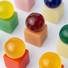 Glanzende, kleurrijke bollen rusten op bijpassende kubussen, diagonaal gerangschikt op een wit oppervlak — elke vorm roept de speelse en decoratieve uitstraling op van de OBA Zeep Bar Rosevale van Matias Moellenbach. De gladde afwerking van de objecten en de levendige mix van pastel- en felle tinten weerspiegelen de vrolijke uitstraling die zo kenmerkend is voor het merk Matias Moellenbach.