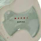 De onderkant van de Serax After Midnight Uil Vaas Lichtblauw XS heeft een glanzende lichtblauwe en beige afwerking, met de merknaam SERAX gedrukt in zwarte hoofdletters.