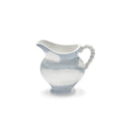 De Serax Wouters & Hendrix Fête Des Bêtes Melkkannetje Lichtblauw, een witte keramieken kan met blauwe lucht- en wolkenpatronen en een kralenhandvat, wordt getoond op een effen witte achtergrond.