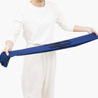 Een persoon in het wit houdt een Shupatto Opvouwbare Boodschappentas Jet Zwart L van Shupatto met zwarte bandjes tegen een witte achtergrond.