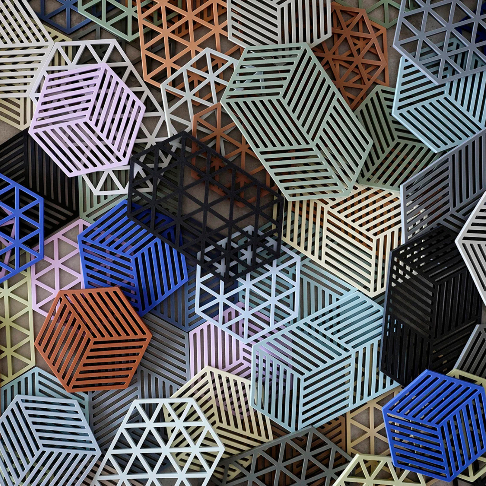 Zone Denmark's Hexagon Trivet Olijfgroen heeft in elkaar grijpende 3D geometrische patronen - voornamelijk kubussen en zeshoeken - in blauw, oranje, zwart en beige met stijlvolle streep- en rasterdetails.